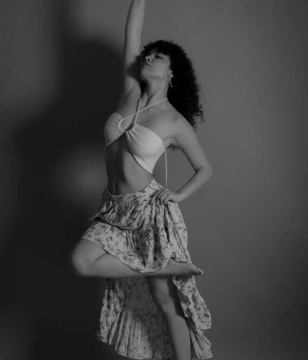 Woman performing a dynamic cardio movement in a dark studio with soft lighting.